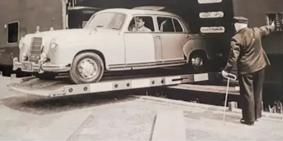 Historical photograph of workers loading cars onto a train